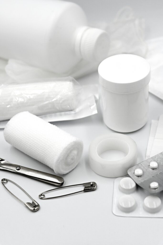 A detailed arrangement of essential first aid supplies including bandages, safety pins, and medication.